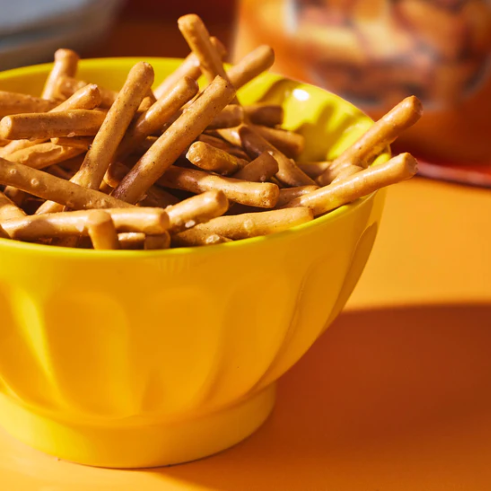 Yellow bowl filled with pretzel sticks on a wooden surface