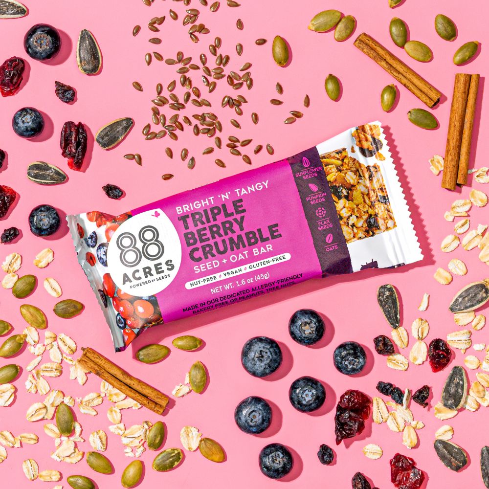 Triple Berry Crumble Seed + Oat Bar on pink background with ingredients